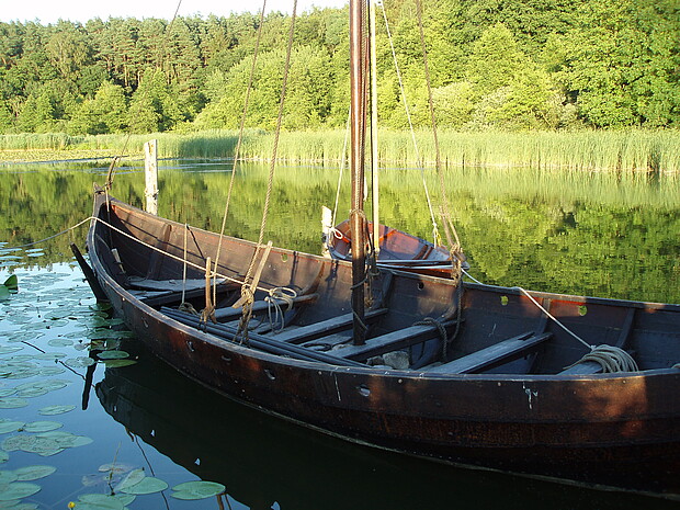 Nachbau eines frühmittelalterlichen Boots Rekonstruiertes Holzboot am Ufer eines Flusses