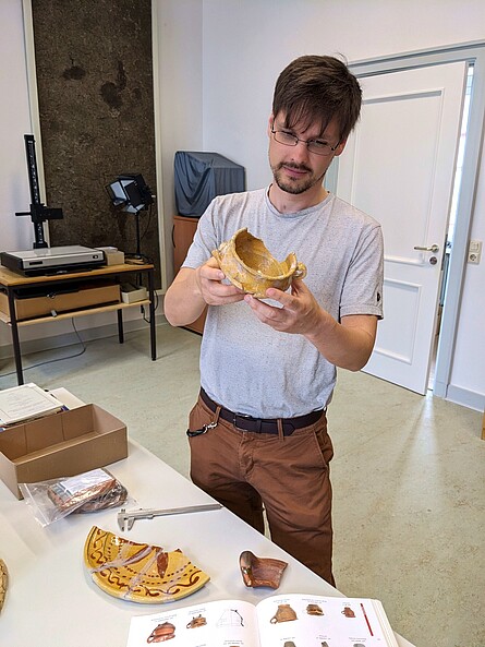 Herr Becker steht hinter einem Tisch mit ausgelegten Scherbenfunde.