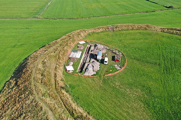 Drohenfoto der Grabungssituation Borgsumburg mit Grabungsschnitt, bauwagen und Fahrzeugen von oben.